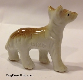 The right side of a bone china figurine that is a tan and white Coyote in a standing pose. Showing the "Japan" engraving on its side.