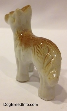 The front left side of a tan and white bone china Coyote figurine in a standing pose. The back of its legs are connected together.