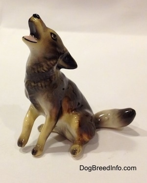 The front left side of a black, tan and white Coyote figurine in a holwing pose.