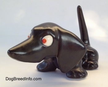 The front left side of a black Dachshund figurine. The figurine has red eyes.