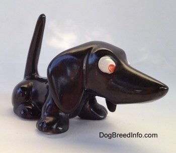 The front right side of a black Dachshund figurine. Thefigurine has no mouth and it has big ears.