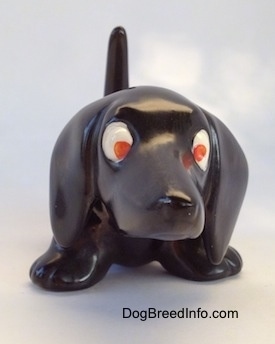 A black Dachshund figurine. The figurine has big paws, big ears and red eyes.