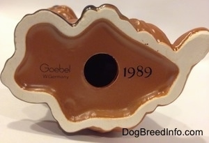The underside of a figurine of a Dachshund puppy and it has a holde in the bottom. To the left of the hole is a number - 1989 - and to the right is the word logo of Goebel W.Germany.