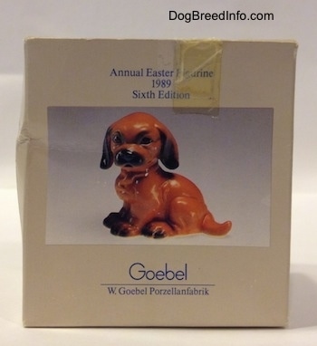 A box with a photo of a figurine that is a Dachshund puppy in a sitting pose.