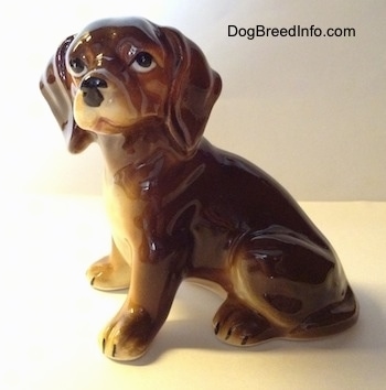 The left side of a glossy brown with tan ceramic Dachshund figurine. The figurine has great details, big ears and big paws.