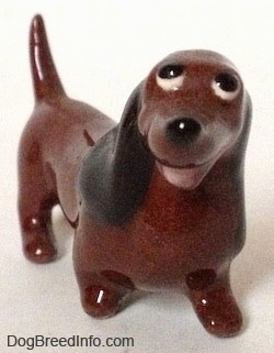 A figurine of a brown Dachshund named 'Dachsie'. The figurine has an open mouth and short appendages.