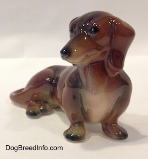 A brown and black Dachshund figurine in a sitting pose.