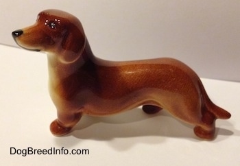 The left side of a brown Dachshund figurine. The figurine has a small ear that is hard to differentiate from its body.