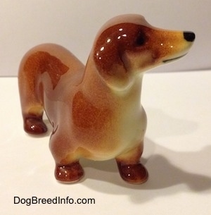 A brown Dachshund figurine. The figurine has short legs and brown paws.