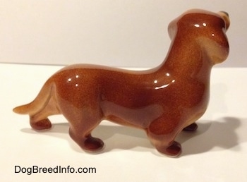 The right side of a brown Dachshund figurine. The figurine has a long body.