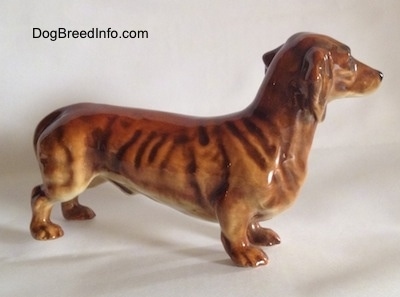 The right side of a brown Dachshund figurine. The figurine has a long body and it has fine details.