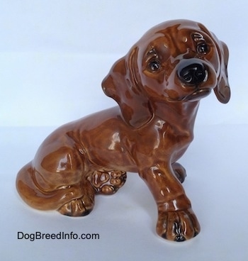 The right side of a brown Dachshund puppy figurine in a sitting pose. The figurine has black circles for eyes.