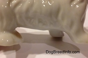 Close up - The side of a porcelain Dachshund figurine with a letter/number engraved into the side of the dog.
