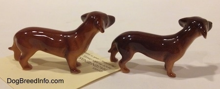 The right side of two Dachshund Mama standing figurines. It is hard to tell the difference between the tail of the figurine from the body.