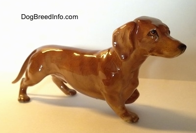 The front right side of a pointing porcelain Dachshund figurine. The figurine is very detailed.