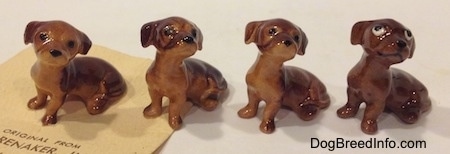 The front left side of four Dachshund Pup Seated figurines. The figurines lack paw details.