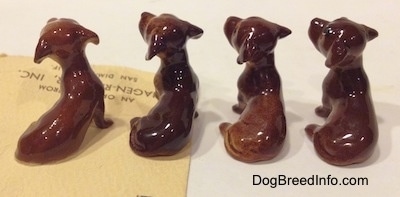 The back side of four Dachshund Pup Seated figurines. The tails of the figurines are hard to differentiate from the body.