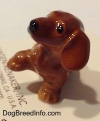 Topdown view of a Dachshund Puppy Seated Paw Up figurine. The figurine has big wide paws.