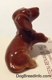 The right side of a Dachshund Puppy Seated Paw Up figurine. The figurine has a medium sized tail.