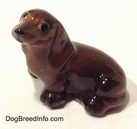 Topdown view of a Dachshund sitting figurine. The ears of the figurine are attached to the body.