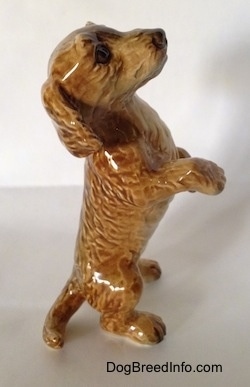 The right side of a tan porcelain Dachshund figurine that is in a begging pose. The figurine has a medium sized tail.