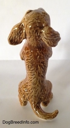 The back of a porcelain tan Dachshund figurine in a begging pose. The figurine has long ears.