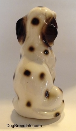 The back of a Dalmatian figurine that is in a sitting pose. The tail of the figurine is hard to differentiate from its body and it has large black ears.