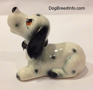 The left side of a hand painted Dalmatian puppy figurine. The figurine has cartoony features. It has long ears and short limbs.