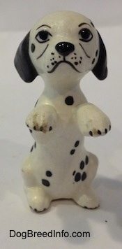 A Dalmatian puppy figurine that is in a begging pose. The figurine has cartoony painted on details. 