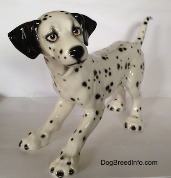 The front left side of a detailed Dalmatian figurine that has long limbs and a long body.