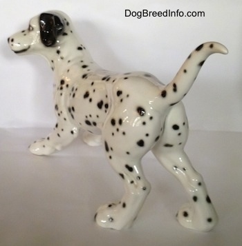 The back left side of a figurine that is of a Dalmatian. The figurine has a detailed face and large ears.