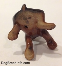 The underside of a Doberman Pinscher puppy figurine. There is a hole on the bottom of the figurine.