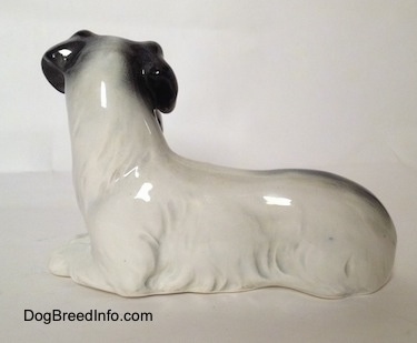 The left side of a figurine of a white and black Doxie laying down.