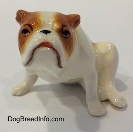 A white with red Bulldog figurine that is in a sitting pose. The figurine has cartoon style eyes.