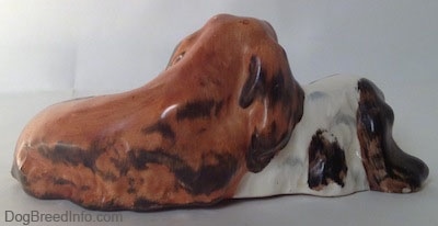 The right side of a figurine of two English Cocker Spaniel dogs that are laying down on top of each other. The ears of the figurines look like the rest of its body.