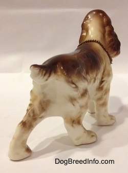 The back right side of a porcelain brown and white English Cocker Spaniel figurine. The figurine has a short tail and a medium sized body.