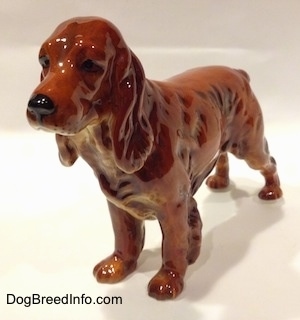 The front left side of a figurine that is of a red English Cocker Spaniel. The figurine has a detailed face.