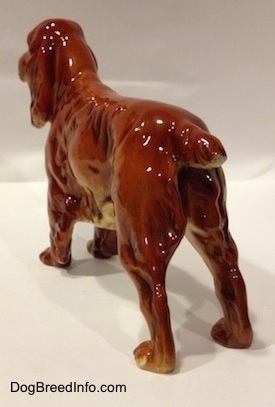 The back left side of a figurine that is of a red English Cocker Spaniel. The tail of the figurine is hard to tell the difference from its body.