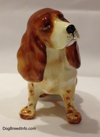 A ceramic figurine of a red and white English Cocker Spaniel in a sitting position figurine. The figurine has great face details.