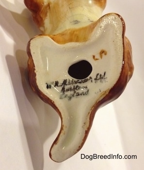 Close up - The underside of a English Cocker Spaniel figurine. The figurine has a hole in the bottom and there are words stamped on the bottom.