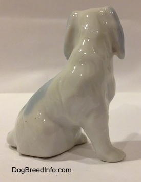 The right side of a white with blue bone china English Setter figurine.  The tail of the figurine is sticking straight up in the air. From the back angle it is hard to differentiate the ears from the head of the figurine.