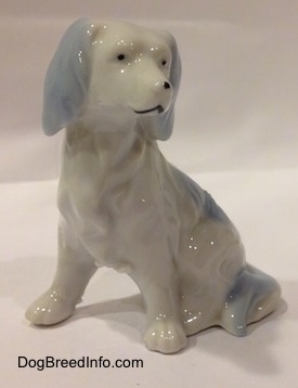 The front left side of a white with blue English Setter figurine. The eyes of the figurine has black dots for eyes.