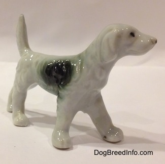 The front right side of a bone china figurine that is of a black and white English Setter. The figurine has a black ear and a white ear. The ears are hard to differentiate from its body.