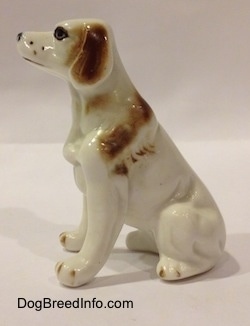 The left side of a white with brown bone china English Setter figurine. The figurine has brown brushings along its body.