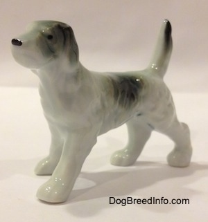 The front left side of a bone china figurine of a black and white English Setter. The figurine has long legs and small paws.