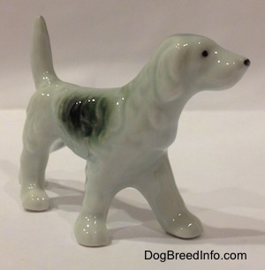 The front right side of a figurine of a bone chine black and white English Setter. The figurine has a black spot with hair details on its right side.
