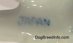Close up - The underside of a bone china figurine. The word - JAPAN - is stamped on the underside.