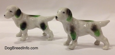 The left side of two bone china English Setter figurines with green and black markings. Both of the figurines tails are in the air.