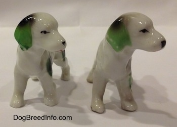 Two English Setter bone china figurines that are white with green and black. The figurines have large black and green ears.