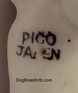 Close up -  The underside of a English Setter bone china figurine. THe figurine has the words - PICO JAPEN - stamped on its underside and there is a hole inside the stamp.